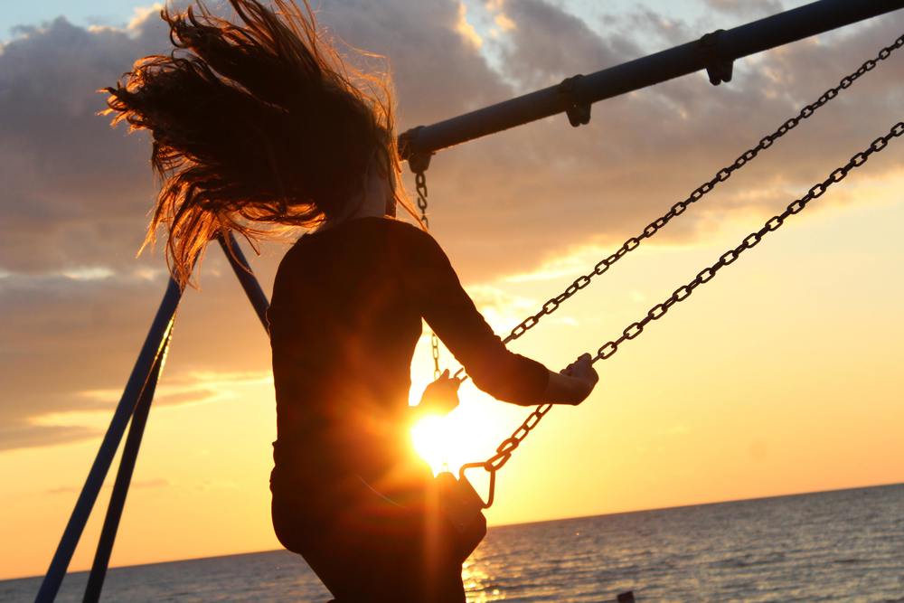 girl on swing sunset in background