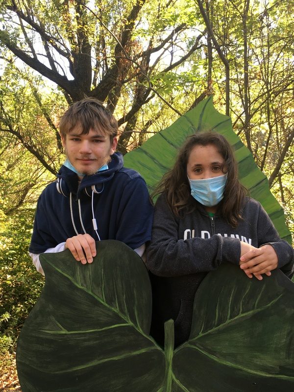 Two students pose behind a large leaf at NY Botanical Gardens