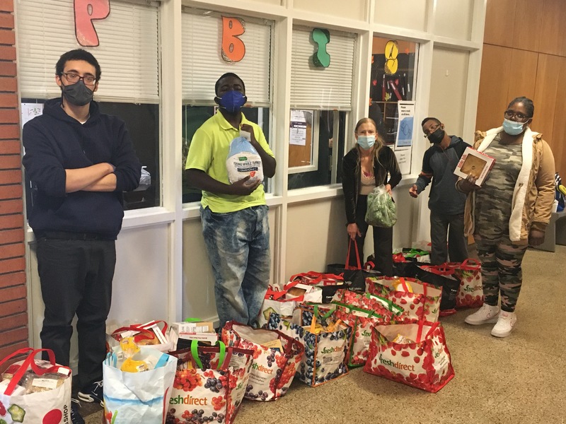 Students and teacher Ms.Sheridan pose with the food they bagged for distribution in front of the main office