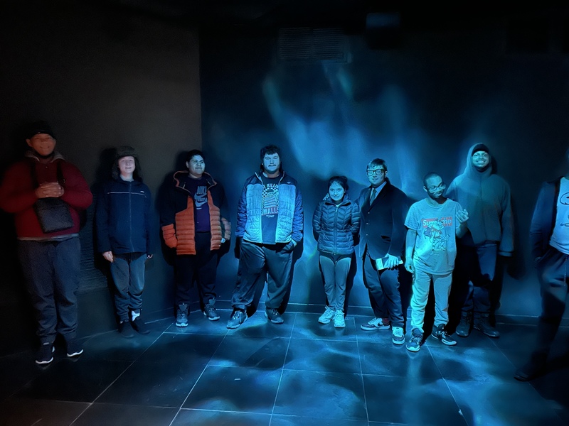 a group of students pose inside the museum surrounded by blue lighting