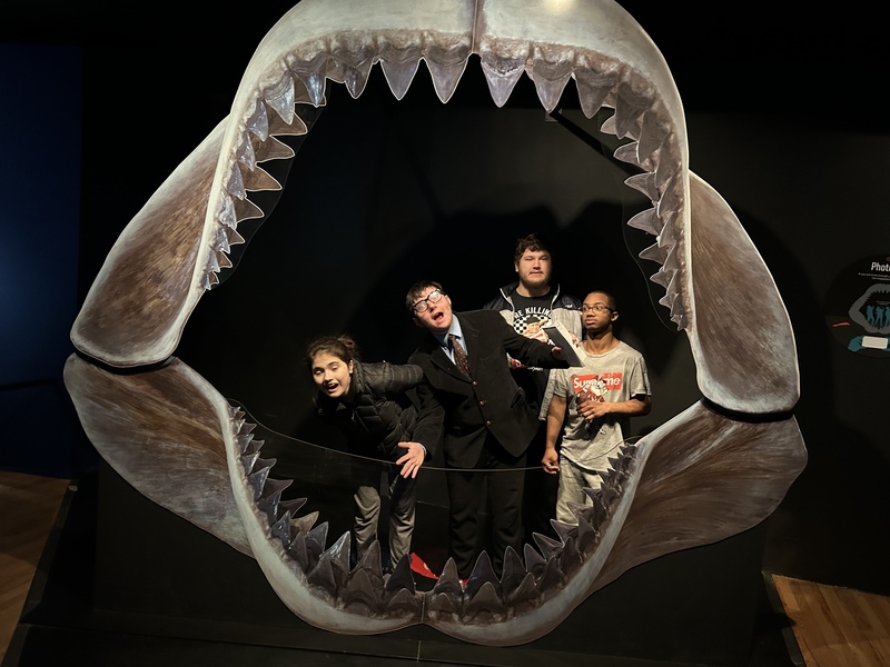 The students pose inside the skeleton mouth of a shark