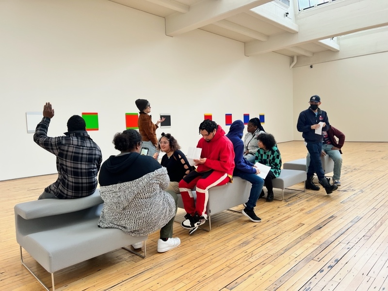 students sit in the museum listening to the art guide