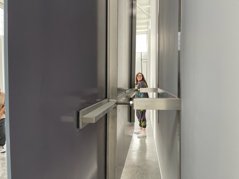 student poses on the other side of a narrow metal exhibit