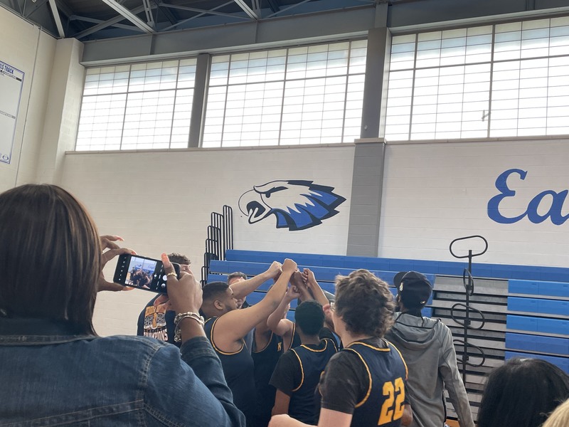 the unified basketball team stands in a circle with their fists raised together while everyone takes their photo